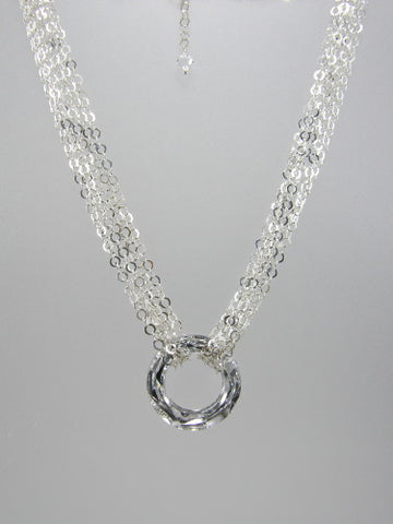 Flat round sterling silver chain triple-wrapped around 30 mm round silver crystal ring pendant.